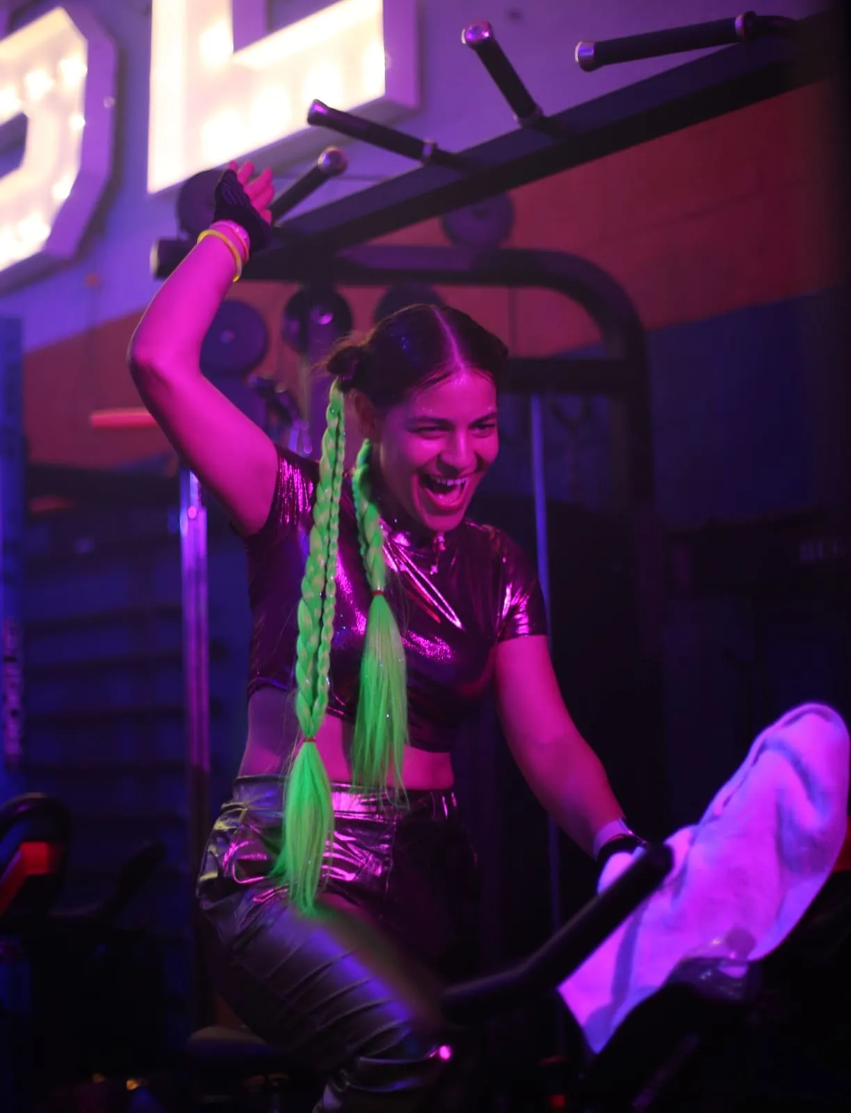 Rider on a spin bike under neon lights at 21 DOSE